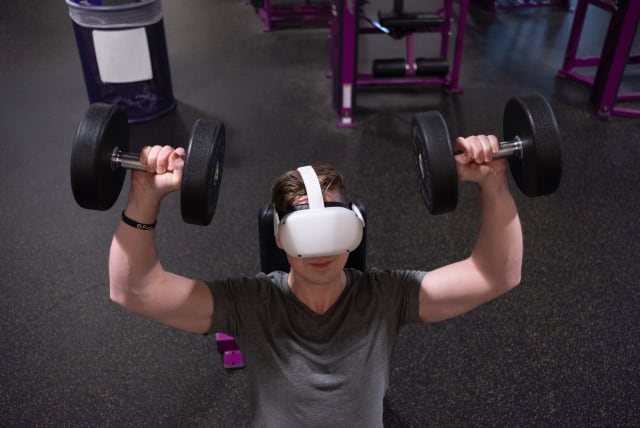  A man lifting weights while wearing a virtual reality headset. (photo credit: Eugene Capon/Pexels)