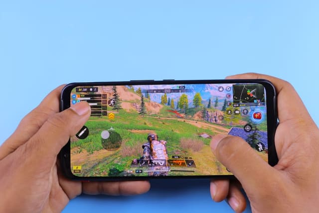  Someone playing a mobile game on their phone (photo credit: PXFUEL)
