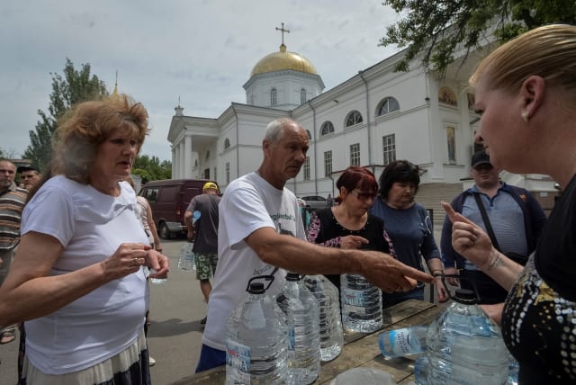  Local residents take drinking water, amid Russia's attack on Ukraine, after the Nova Kakhovka dam breached, in Kherson, Ukraine June 10, 2023. (photo credit: REUTERS)