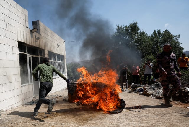  A Palestinian man runs near a burning object, after an attack by Israeli settlers, near Ramallah, in the West Bank, June 21, 2023 (photo credit: REUTERS/MOHAMAD TOROKMAN)