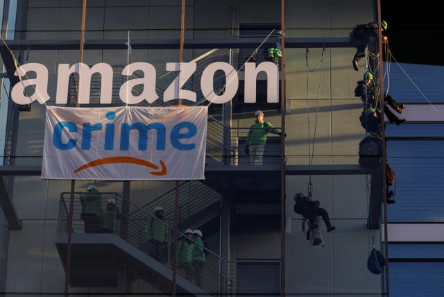Activists of Greenpeace attach a banner reading 'crime', which looks like the 'Amazon prime' logo at the Amazon headquarters in Munich, Germany, November 25, 2022 (photo credit: REUTERS/Lukas Barth)