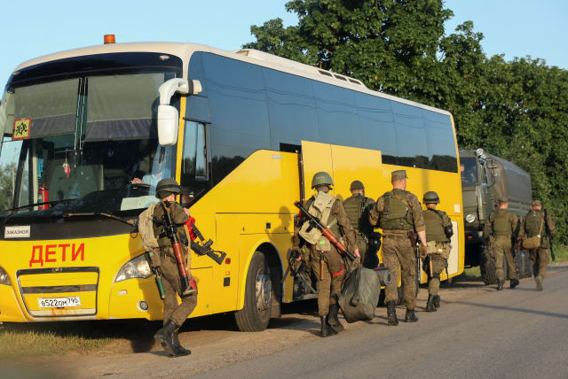 Russian service members move into positions, as part of a counter-terrorist operation declared after an armed mutiny by the Wagner mercenary group, in the Moscow region, Russia, June 24, 2023. A sign on a bus reads: "Children". (photo credit: STRINGER/ REUTERS)
