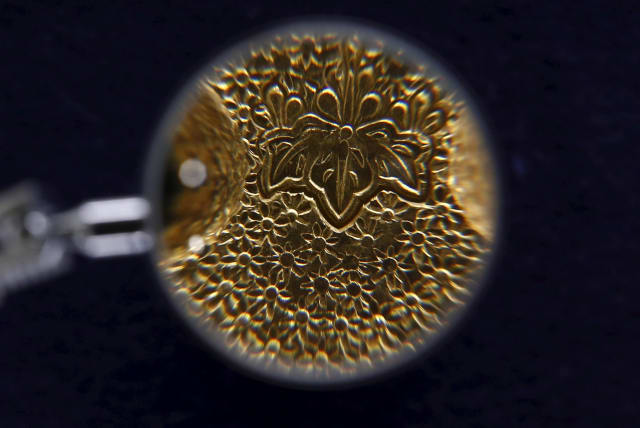 A detail of the engraving on a Japanese gold ingot that was in use between the 16th and 17th centuries is seen enlarged under a magnifying glass, at the Currency Museum of the Bank of Japan in Tokyo, November 18, 2015. Picture taken November 18, 2015. (photo credit: THOMAS PETER/REUTERS)