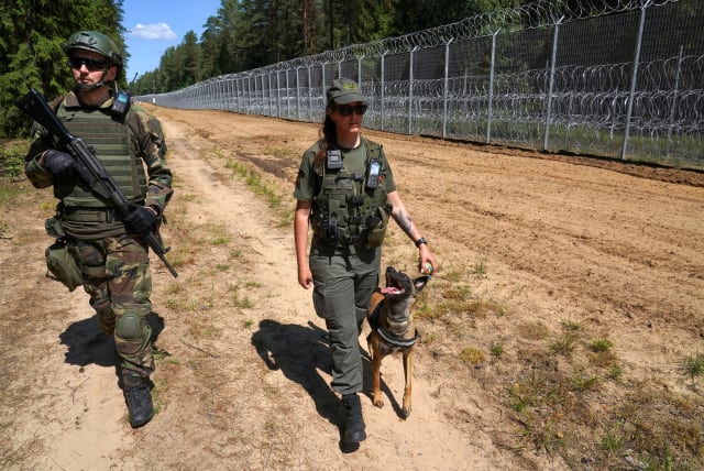 A member of Lithuanian Riflemen's Union and a Border Guard officer patrol along Belarus border in Kaniukai, Lithuania July 7, 2023. (photo credit: REUTERS/JANIS LAIZANS)