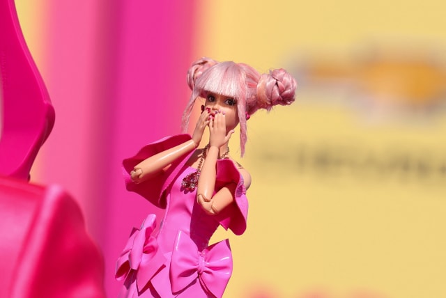 A fan takes a photo of a Barbie doll at the world premiere of the film "Barbie" in Los Angeles, California, U.S., July 9, 2023 (photo credit: MIKE BLAKE/REUTERS)