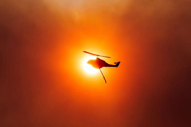  A firefighting helicopter is silhouetted in front of the sun, as a wildfire burns in Mandra, Greece, July 18, 2023. (photo credit: ALKIS KONSTANTINIDIS / REUTERS)