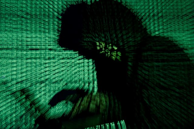 A man holds a laptop computer as cyber code is projected on him in this illustration picture taken on May 13, 2017. (photo credit: KACPER PEMPEL/ILLUSTRATION PHOTO/REUTERS)