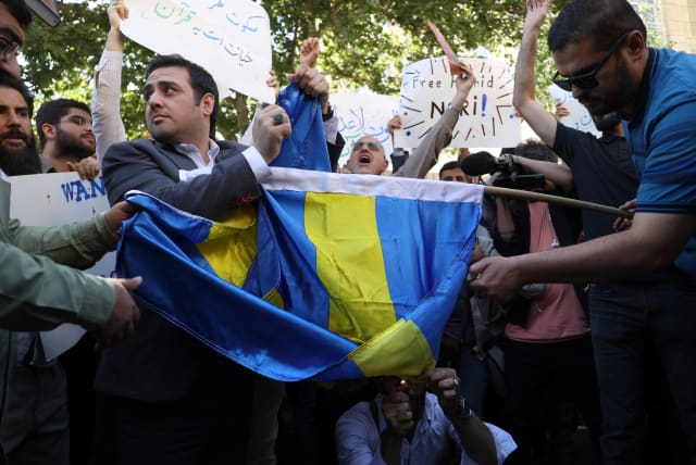  Demonstrators burn the Swedish flag during a protest against a man who burned a copy of the Quran outside a mosque in the Swedish capital Stockholm, in front of the Swedish Embassy in Tehran, Iran June 30, 2023 (photo credit: MAJID ASGARIPOUR/WANA)