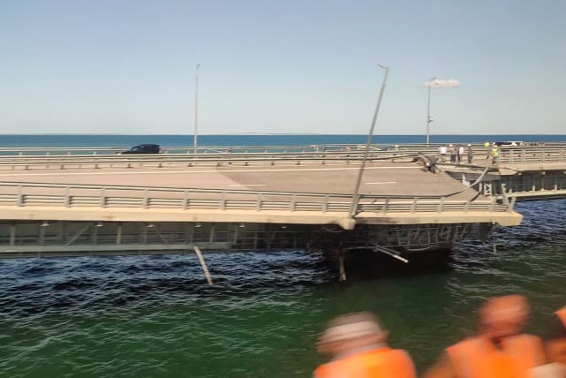 A view through a train window shows the section of a road split and sloping to one side following an alleged attack on the Crimea Bridge, that connects the Russian mainland with the Crimean peninsula across the Kerch Strait, in this still image from video taken July 17, 2023.  (photo credit: STRINGER/ REUTERS)