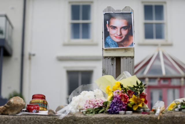  A picture of late singer Sinead O'Connor, who died at the age of 56, known for her chart-topping hit "Nothing Compares 2 U", is placed around floral tributes outside her former Irish home, in the seaside town of Bray in County Wicklow, Ireland, July 27, 2023. (photo credit: REUTERS)