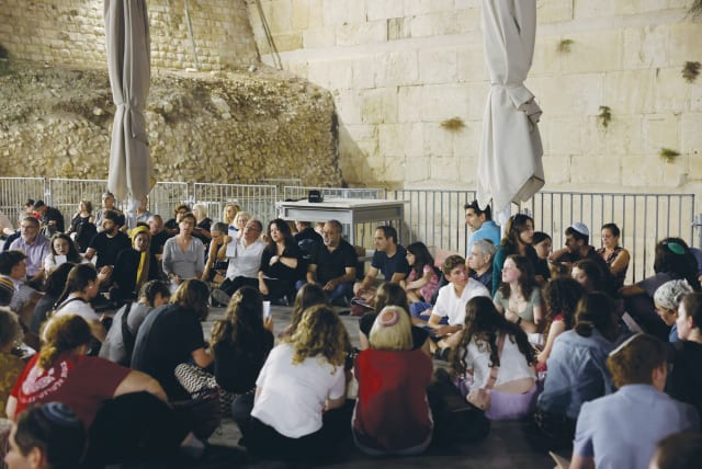  MEN, WOMEN, and children sit at the Ezrat Yisrael section of the Western Wall Wednesday night to read Eicha (the Book of Lamentations) at the start of the Tisha Be’av fast. (photo credit: MARC ISRAEL SELLEM/THE JERUSALEM POST)