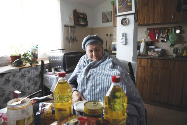  A HOLOCAUST survivor examines foodstuffs she received from a nonprofit aiding impoverished survivors, in Beit Shemesh.  (photo credit: RONEN ZVULUN/REUTERS)