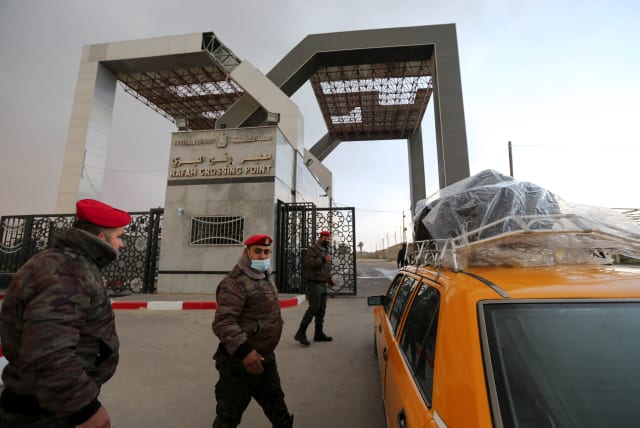  Members of Palestinian security forces keep watch as a taxi carrying passengers arrives at the gate of Rafah border crossing with Egypt, in the southern Gaza Strip February 23, 2021.  (photo credit: IBRAHEEM ABU MUSTAFA/REUTERS)