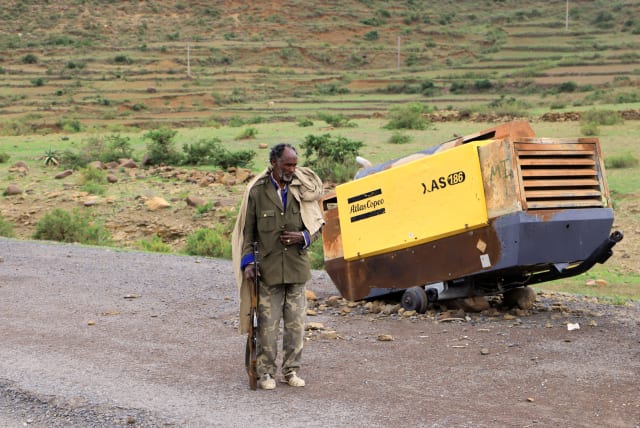  A Tigrayan Militia member stands next to construction machinery destroyed during the fighting between the Tigray People's Liberation Front (TPLF) and Ethiopian National Defence Force (ENDF) allied with Amhara Special Forces and Eritrean Defence Forces (EDF) on the outskirts of Samre, Ethiopia. (photo credit: Tiksa Negeri/Reuters)