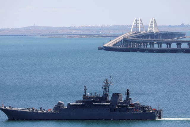  A Russian Navy amphibious landing ship that was deployed to transport cars across the Kerch Strait, moves near the Crimean Bridge, a section of which was damaged by an alleged overnight attack, as seen from the city of Kerch, Crimea, July 17, 2023. (photo credit: REUTERS/ALEXEY PAVLISHAK)