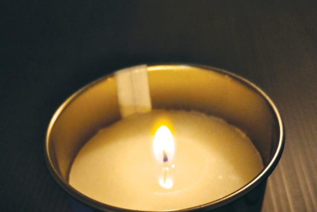  A MEMORIAL candle is lit for a deceased loved one. 