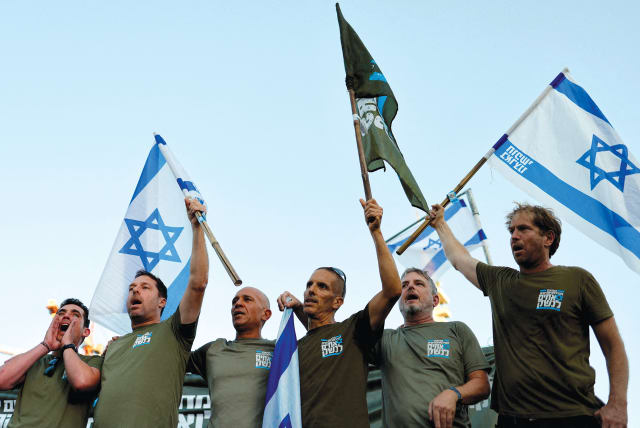 IDF reservists sing in unison near the Defense Ministry in Tel Aviv after signing a pledge on July 19 to suspend their voluntary service in the military in protest of the judicial reform legislation. (photo credit: AMIR COHEN/REUTERS)
