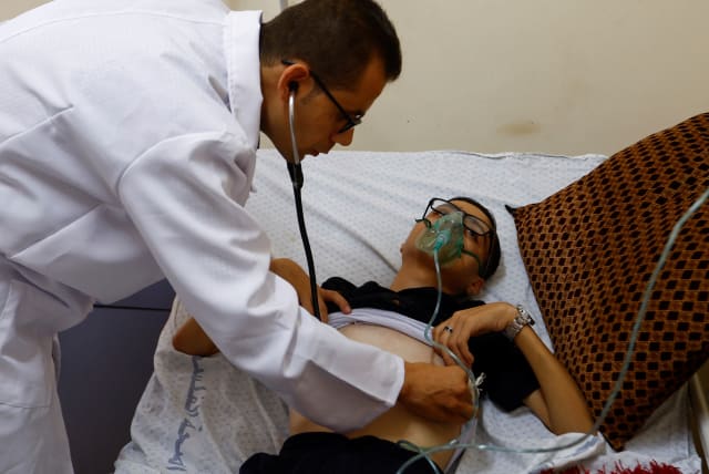  A Palestinian doctor checks Abdul Majeed al-Sabakhi as he struggles to breathe at Shohda Al Aqsa hospital amid a heatwave in Deir Al-Balah, central Gaza Strip, July 25, 2023. (photo credit: IBRAHEEM ABU MUSTAFA/REUTERS)