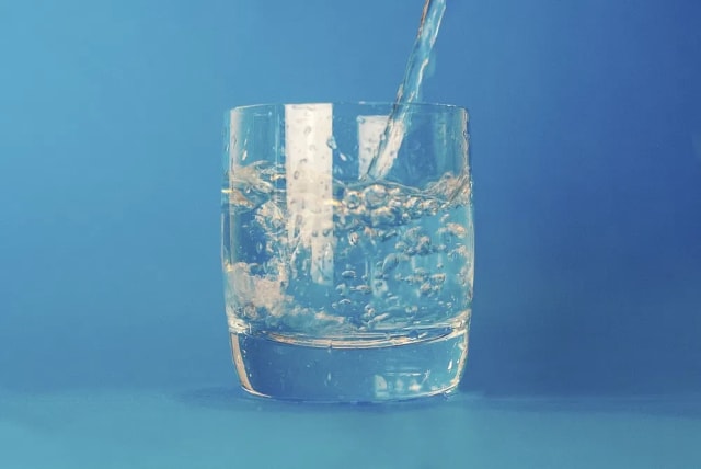  A clear glass of drinking water against a blue background. (photo credit: RAWPIXEL)