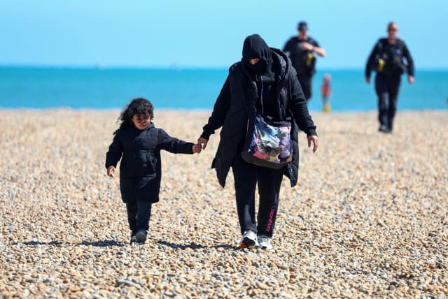  People, believed to be migrants, walk in Dungeness, Britain, August 16, 2023.  (photo credit: TOBY MELVILLE/REUTERS)