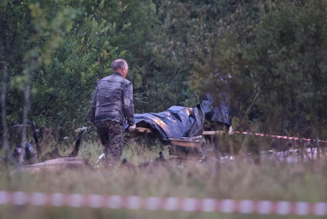 Emergency specialists carry a body bag near wreckages of the private jet linked to Wagner mercenary chief Yevgeny Prigozhin near the crash site in the Tver region, Russia, August 24, 2023 (photo credit: REUTERS/MARINA LYSTSEVA)