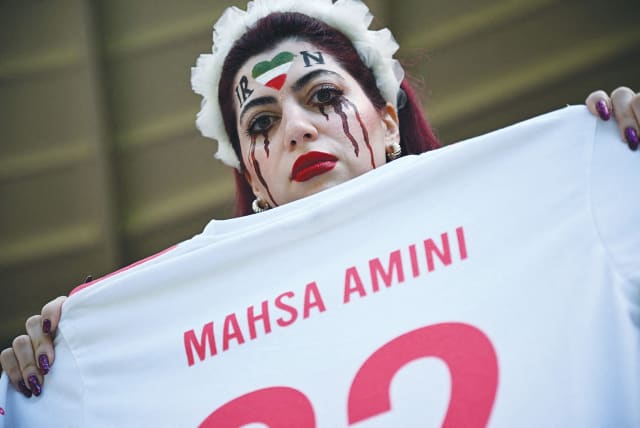  AN IRANIAN fan holds a jersey in memory of Mahsa Amini, inside the stadium before a World Cup soccer match between Iran and Wales, in Qatar, last November.  (photo credit: DYLAN MARTINEZ/REUTERS)