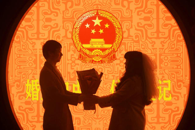 A newly wed couple pose for pictures on Valentine's Day at a marriage registration office in Hangzhou, Zhejiang province, China February 14, 2023. (photo credit: CHINA DAILY VIA REUTERS)