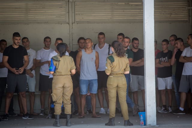 Young Israelis line up as they arrive to an Israeli army recruitment center at Tel Hashomer, outside of Tel Aviv on July 26, 2018 (photo credit: MIRIAM ALSTER/FLASH90)