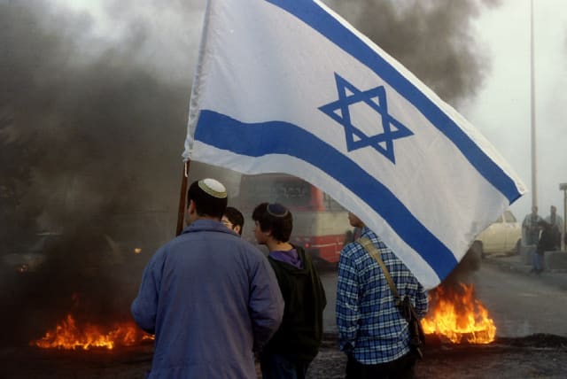  Right-wing Jewish settlers in front of a burning barricade as they block a main road from the West Bank. December 2, 1993 (photo credit: REUTERS)
