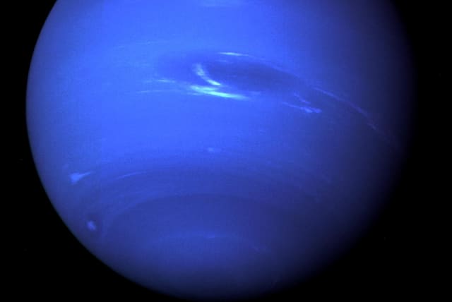The "Great Dark Spot", a storm in the atmosphere and the bright, light-blue smudge of clouds that accompanies the storm is seen on the planet Neptune, taken by the NASA spacecraft Voyager 2 less than five days before its closest approach of the planet on August 25, 1989. (photo credit: NASA/JPL-CALTECH/HANDOUT VIA REUTERS)