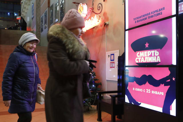 People walk past a poster of the movie "Death of Stalin" at a cinema in Moscow, Russia January 23, 2018. Picture taken January 22, 2018. (photo credit: SERGEI KARPUKHIN/REUTERS)