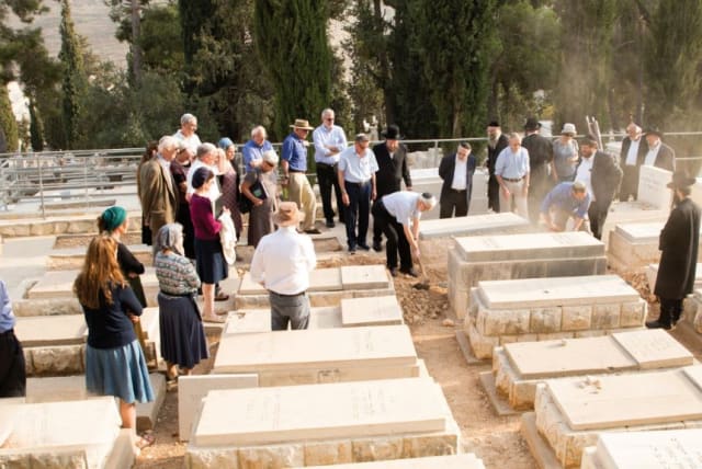  FAMILY MEMBERS cover the remains with the soil of Jerusalem. (photo credit: Olivestone family)