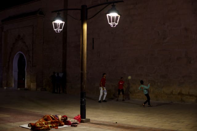  People play soccer next to a woman resting on the sidewalk in Marrakesh, following a powerful earthquake in Morocco, September 9, 2023.  (photo credit: REUTERS/HANNAH MCKAY)