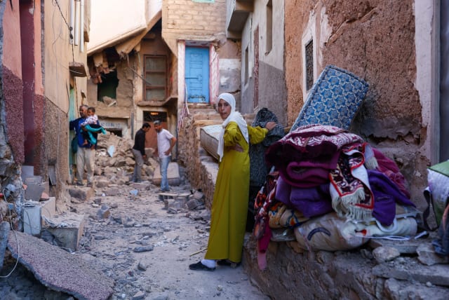  A woman looks on as people inspect damaged buildings, in the aftermath of a deadly earthquake in Moulay Brahim, Morocco, September 10, 2023. (photo credit: REUTERS/HANNAH MCKAY)