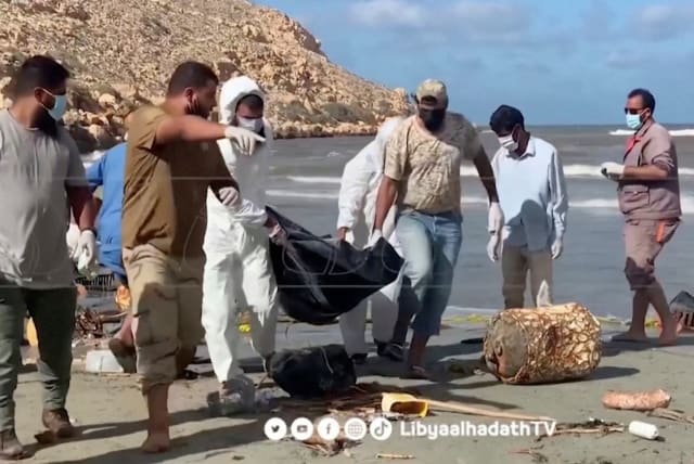  Volunteers carry bodies pulled out of the sea following deadly floods, in Derna, Libya in this still image obtained from a handout video released September 14, 2023 (photo credit: REUTERS)