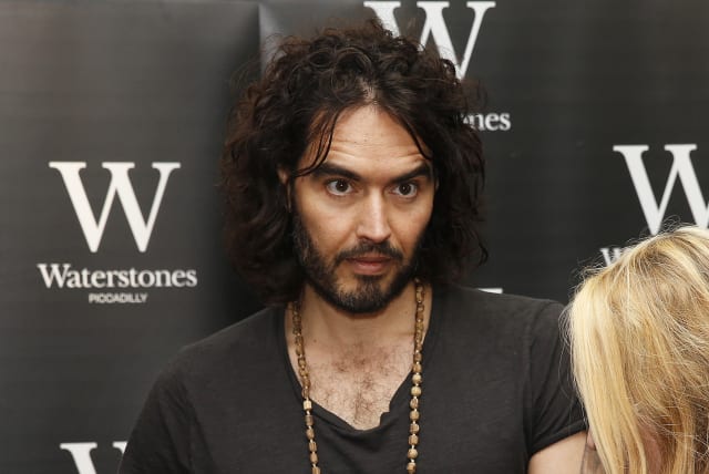 Comedian Russell Brand signs a copy of his new book entitled "Revolution" for fan Amber Smith of Hastings, in central London, December 5, 2014. (photo credit: REUTERS/SUZANNE PLUNKETT)