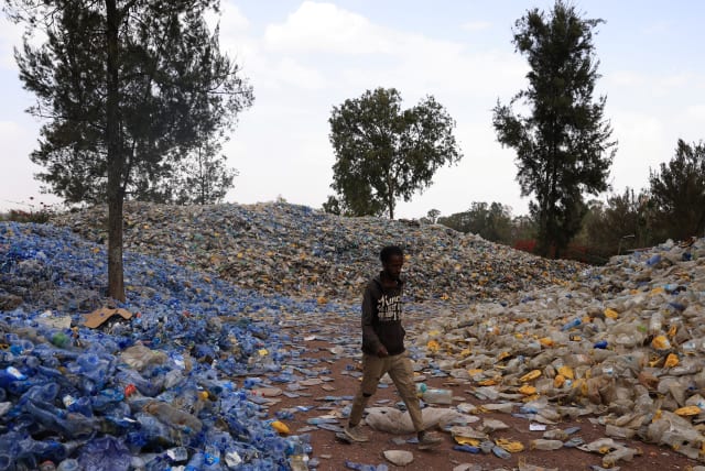  A labourer walks in a sorted piles of recyclable plastic bottles in Addis Ababa, Ethiopia June 2, 2022 (photo credit: REUTERS/TIKSA NEGERI)