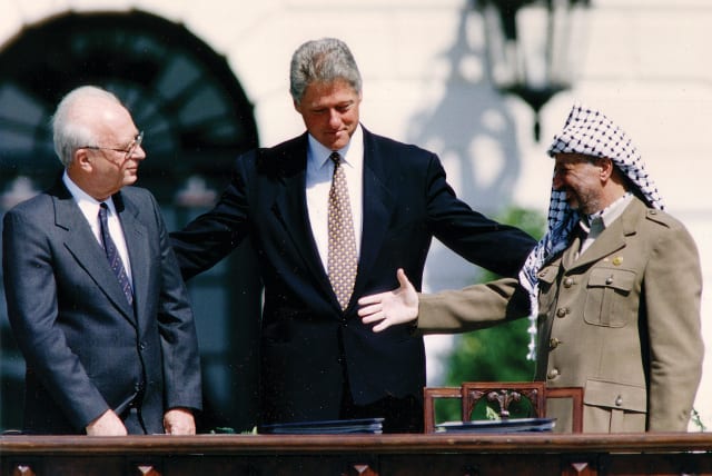  PLO CHAIRMAN Yasser Arafat reaches to shake hands with prime minister Yitzhak Rabin, as US president Bill Clinton stands between them, after the signing of the Israeli-PLO peace accord, at the White House in Washington, on September 13, 1993. (photo credit: GARY HERSHORN/REUTERS)