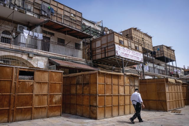  A MAN walks past a row of ‘sukkot,’ temporary dwellings, already built ahead of the holiday, on a street in the Mea She’arim neighborhood, in Jerusalem, last week. (photo credit: Chaim Goldberg/Flash90)