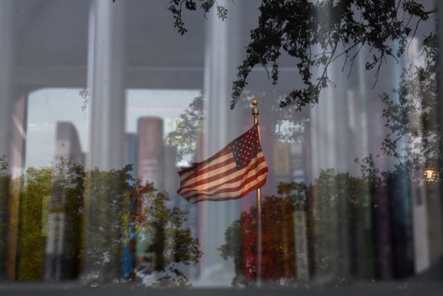  A reflection of an American flag is visible as a Little Free Library, which was designed to look like a prison, invites residents to take books that the library says have been challenged by schools across the state of Texas, in Houston, Texas, U.S. May 3, 2023.  (photo credit: REUTERS/CALLAGHAN O’HARE)