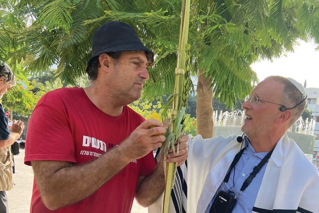  A MAN wearing a shirt with a slogan in support of women’s rights is given the Sukkot Four Species by the writer at yesterday’s prayer service at Dizengoff Square (photo credit: RACHEL SHARON)