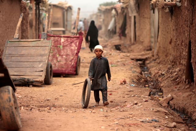  A boy plays with a tyre on an a street in an Afghan refugee camp in Islamabad, Pakistan October 31, 2017. (photo credit: REUTERS/CAREN FIROUZ/FILE PHOTO)