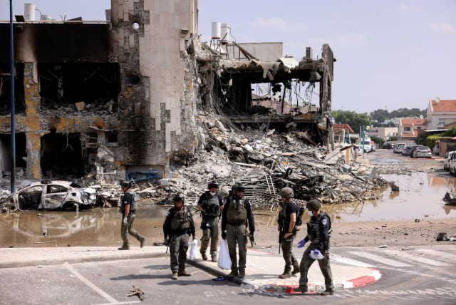  Israeli security gather near a rifle at the site of a battle following a mass infiltration by Hamas gunmen from the Gaza Strip, in Sderot (photo credit: REUTERS/Ronen Zvulun)