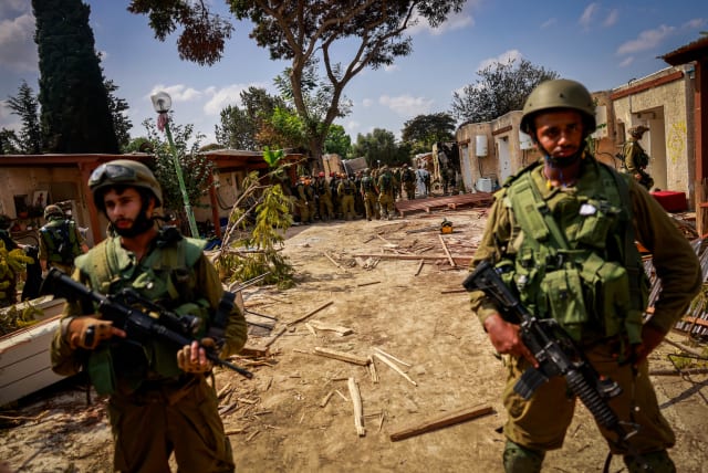  SOLDIERS STAND amid the destruction in Kibbutz Kfar Aza, near the Israel-Gaza border. (photo credit: Chaim Goldberg/Flash90)