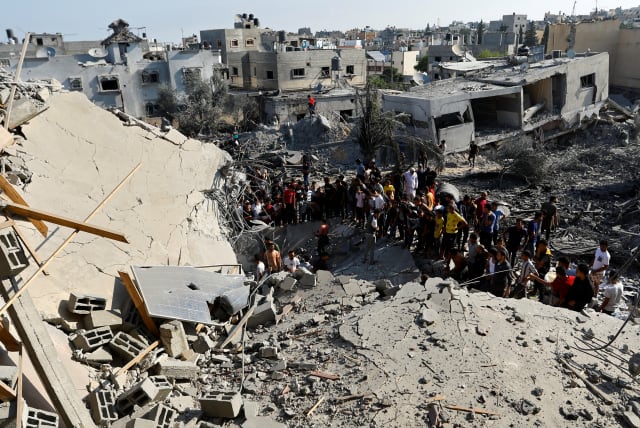  Palestinians gather near the rubble in the aftermath of Israeli strikes, in Khan Younis in the southern Gaza Strip, October 14, 2023. (photo credit: REUTERS/IBRAHEEM ABU MUSTAFA)