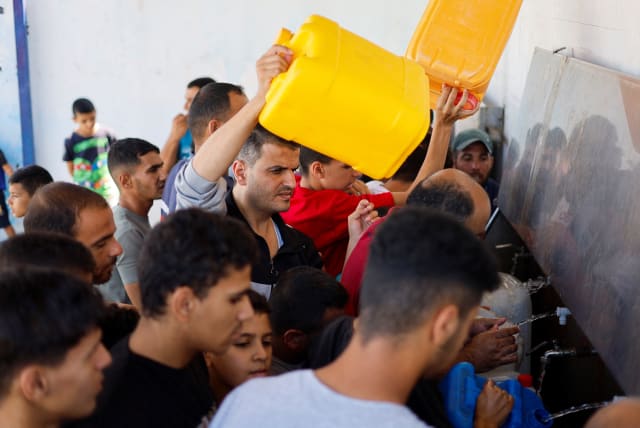  Palestinians gather to collect water, amid shortages of drinking water, as the Israeli-Palestinian conflict continues, in Khan Younis in the southern Gaza Strip October 15, 2023. (photo credit: REUTERS/MOHAMMED SALEM)
