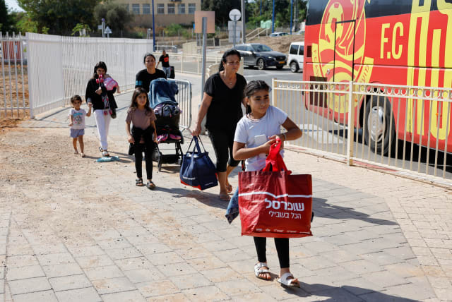 People walk with their belongings next to a bus as Israelis are evacuated from the southern town of Sderot, near Israel's border with Gaza, October 15, 2023. (photo credit: REUTERS/AMIR COHEN)