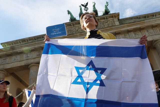  AT THE Brandenburg Gate, in Berlin, last week, an Israel supporter holds the Israeli flag and a sign that reads ‘I stand with Israel.’  (photo credit: REUTERS/Liesa Johannssen)