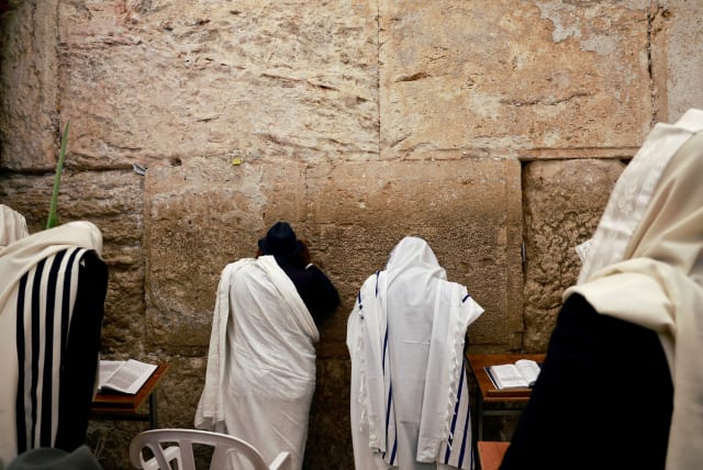  Worshippers wearing prayer shawls take part in the priestly blessing during the Jewish holiday of Sukkot at the Western Wall, Judaism's holiest prayer site, in Jerusalem's Old City, October 2, 2023 (photo credit: REUTERS/AMMAR AWAD)
