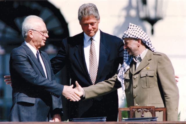  PLO chairman Yasser Arafat shakes hands with Israeli prime minister Yitzhak Rabin as US president Bill Clinton stands between them, after the signing of the Oslo Peace Accords at the White House on September 13, 1993. (photo credit: GARY HERSHORN/REUTERS)
